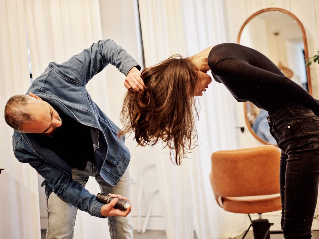A stylist blow-drying a client while preparing a wedding party